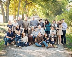 a group of people sitting on the side of a road in front of some trees