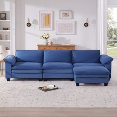 a living room with a blue sectional couch and white rugs on the floor in front of a large window