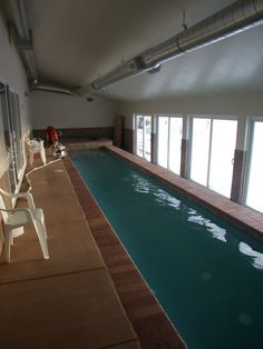 an indoor swimming pool with chairs next to it