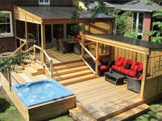 a hot tub sitting on top of a wooden deck next to a patio and covered in red cushions