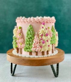 a pink and green decorated cake sitting on top of a wooden stand