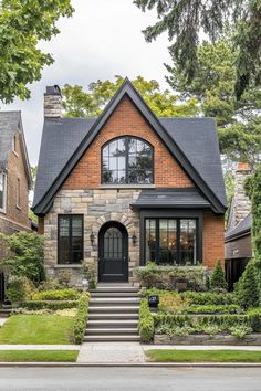 a brick and stone house with black trim on the front door, steps leading up to it