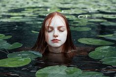 a woman is floating in the water with lily pads