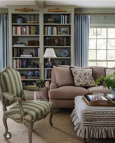 a living room filled with furniture and bookshelves next to a window covered in blue curtains