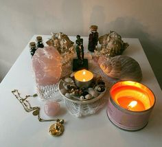 candles, rocks and other items on a white tablecloth with gold chain necklaces