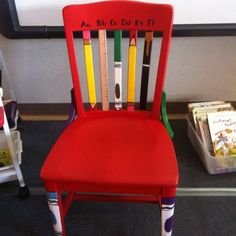 there is a red chair with crayons on it and a book shelf in the background