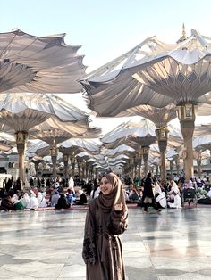 a woman is standing under umbrellas in the middle of an open air market area