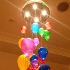 a chandelier made out of balloons hanging from the ceiling with lights above it