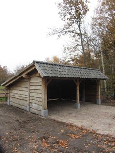 a wooden building with a metal roof in the middle of an open area surrounded by trees