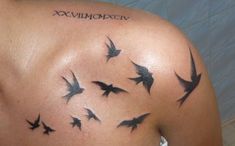 the back of a woman's shoulder with birds flying in the sky and roman numerals on it