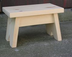 a small wooden step stool sitting on the sidewalk