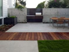 an outdoor patio with table and chairs next to a fenced in area that has grass on both sides