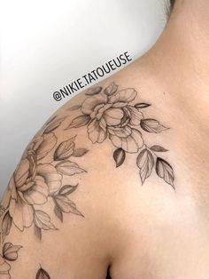 a woman's shoulder with flowers and leaves tattooed on her chest, in front of a white background