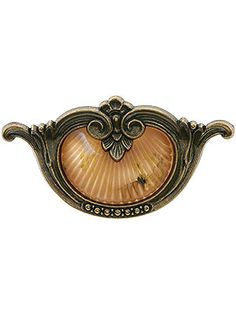 an antique brass drawer pull with a shell in the center