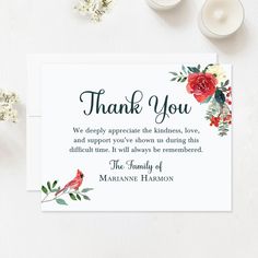 a thank card with red flowers and greenery on it, next to two candles