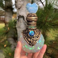 a hand holding up a glass bottle with a blue stone in it's top