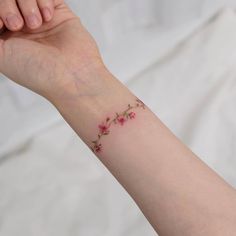 a woman's arm with a flower tattoo on it, and the wrist is covered in pink flowers