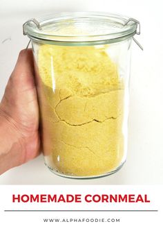 a hand holding a jar filled with cornmeal next to the words homemade cornmeal