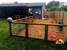 a fenced in area with some hay on the ground and a dog house behind it