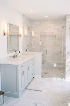 a white bathroom with two sinks and a walk in shower next to a large mirror