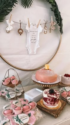 a table topped with cakes and cupcakes next to a wall hanging on the wall