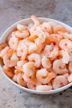 a white bowl filled with shrimp on top of a table