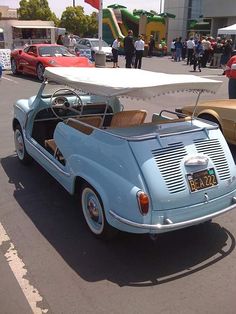 an old car is parked on the side of the road with other cars in the background