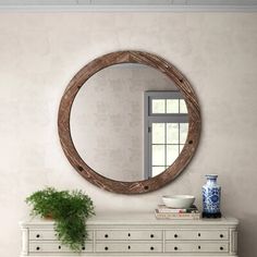 a white dresser with a mirror and potted plant on it next to a window