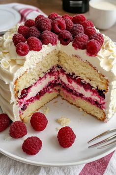 a cake with white frosting and raspberries on top is cut in half