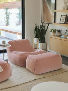 two pink bean bags sitting on top of a rug in front of a large window