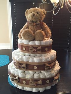 a teddy bear is sitting on top of a diaper cake that is stacked high