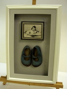 a pair of blue shoes sitting in front of a framed picture with a baby's picture on it