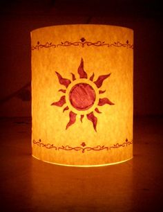 a paper lamp that is lit up with the sun in it's center and surrounded by ornate designs