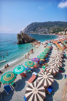 the beach is crowded with umbrellas and people swimming in the water at this time