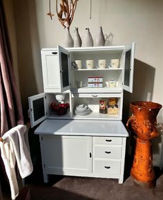 a white cabinet sitting next to an orange vase