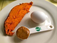 an egg and butter on a plate next to a spoon with some kind of sauce