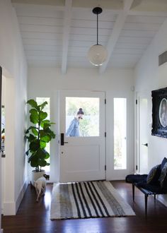 a living room with a rug, chair and potted plant on the side walk