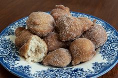 some sugared doughnuts are on a blue and white plate