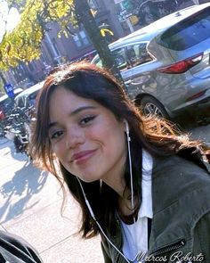 a woman with headphones on standing next to a street