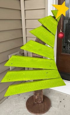 a green wooden christmas tree sitting in front of a door