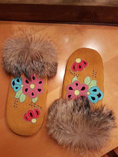 two slippers with flowers on them are sitting on a table next to a fur ball