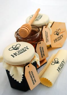 honey jars with labels on them sitting next to each other and some wooden spoons