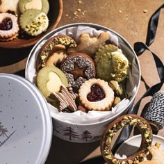 some cookies and pastries are in a tin on the table next to other treats