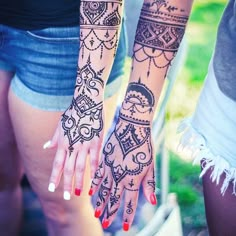 two girls with henna tattoos on their arms and hands, both holding onto each other