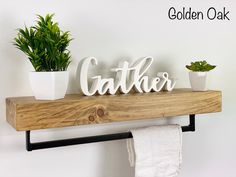 there is a wooden sign that says gather and two potted plants on the shelf