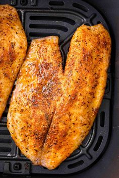 two pieces of chicken sitting on top of an air fryer