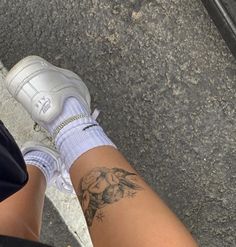 a woman's legs with tattoos on them and white tennis shoes in front of her