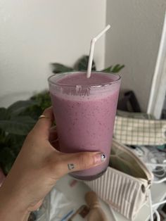 a person holding a glass with a smoothie in it and a straw sticking out of the top