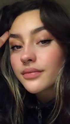 a close up of a person with a nose piercing on her nose and wearing a black shirt