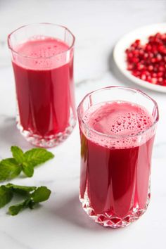 two glasses of pomegranate drink on a table